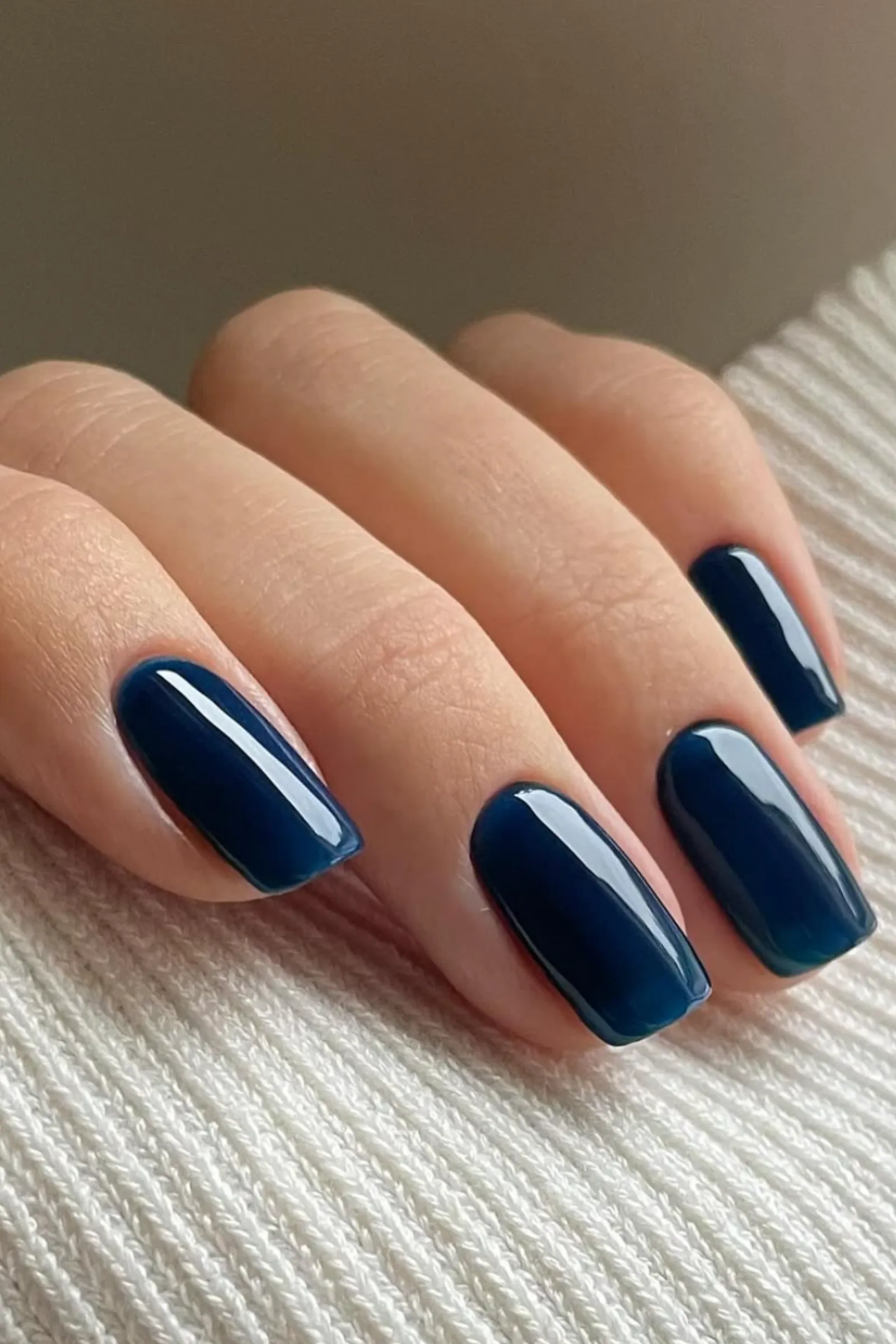 Manicura de uñas azul marino brillantes con forma cuadrada sobre fondo claro